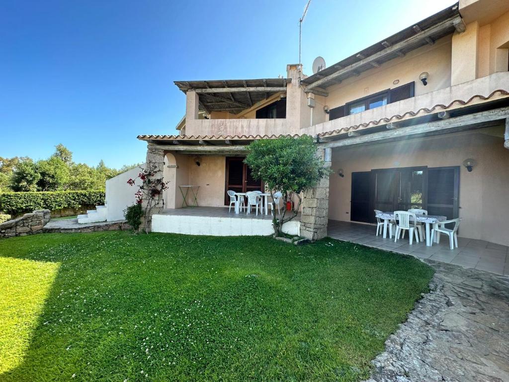 una casa con un cortile con tavoli e sedie bianchi di La Costa Mare a Arzachena