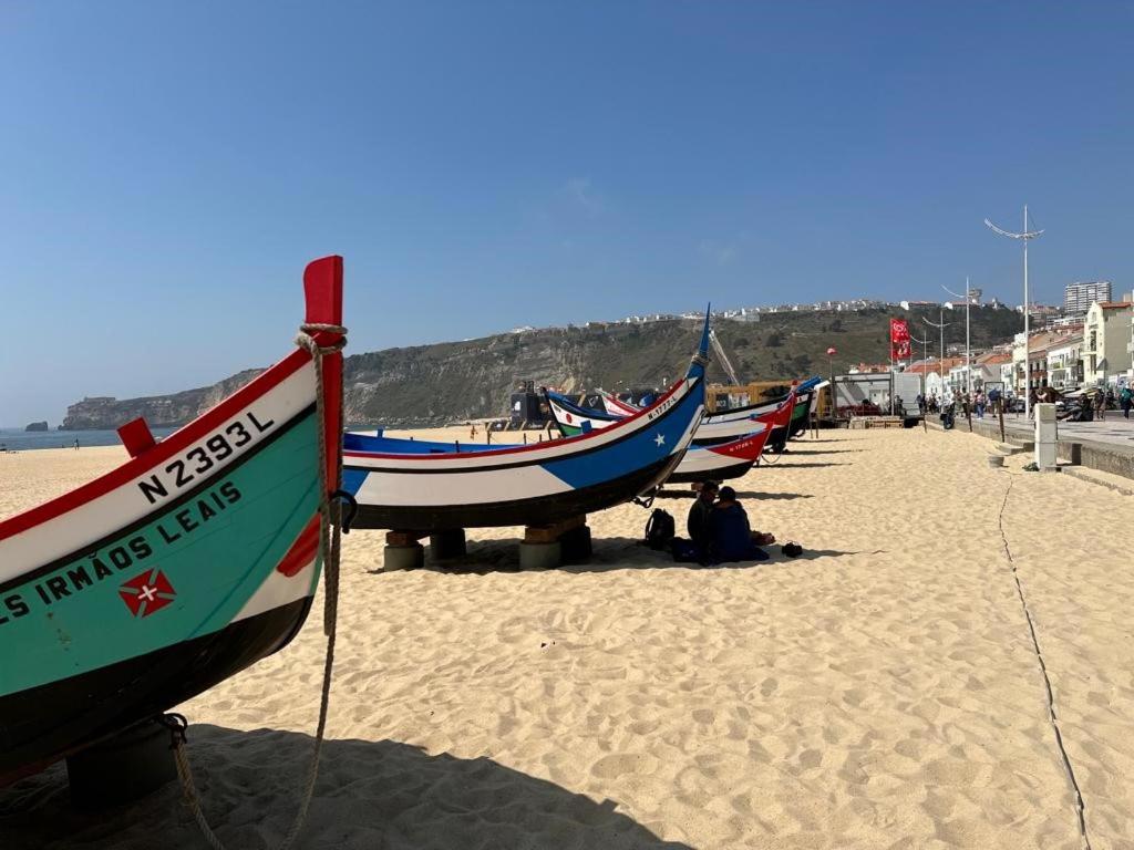una fila de barcos sentados en una playa de arena en 100 Meters from the Beach! Rua da Regeneração Nazaré, en Nazaré