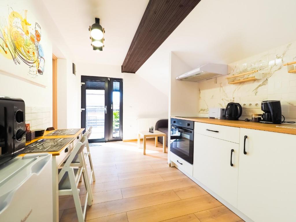 a kitchen with white cabinets and a wooden floor at Ben Apartments in Sibiu
