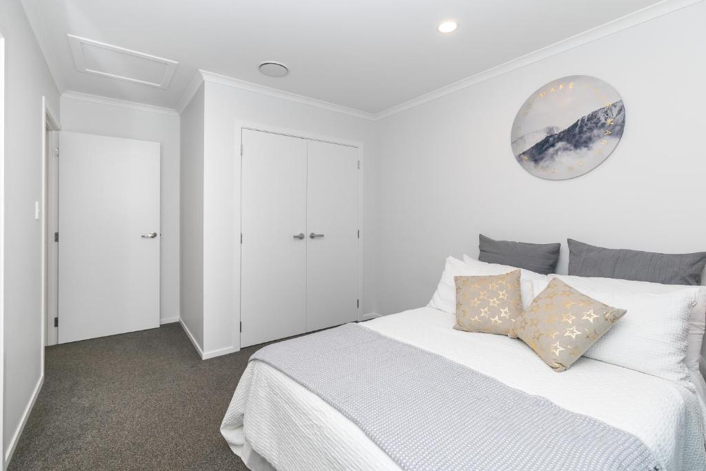 a white bedroom with a large white bed with pillows at Comfy Stay Close to City Center in Hamilton