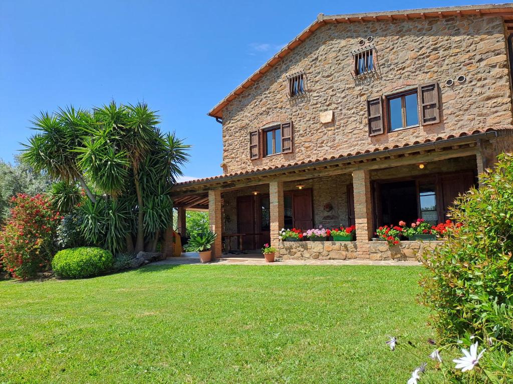 een groot stenen huis met een groene tuin bij Podere Belvedere Villa Classic Tuscan in Magliano in Toscana