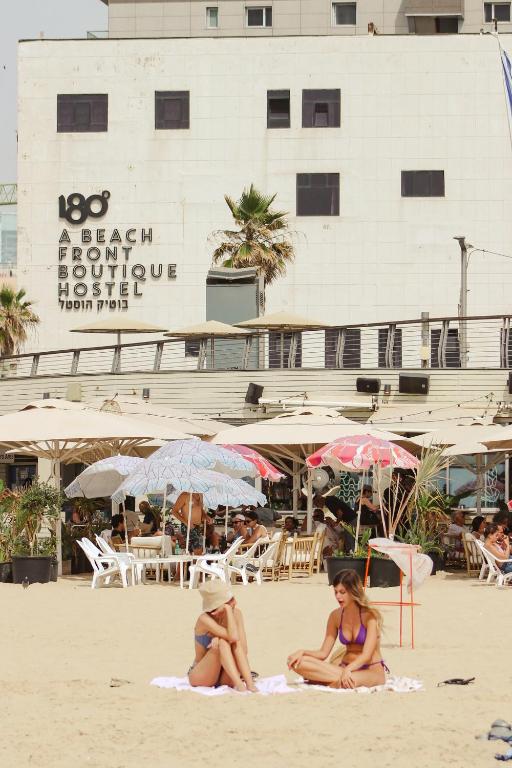 Dos mujeres en traje de baño sentadas en la playa en 180 Boutique Hostel, en Tel Aviv