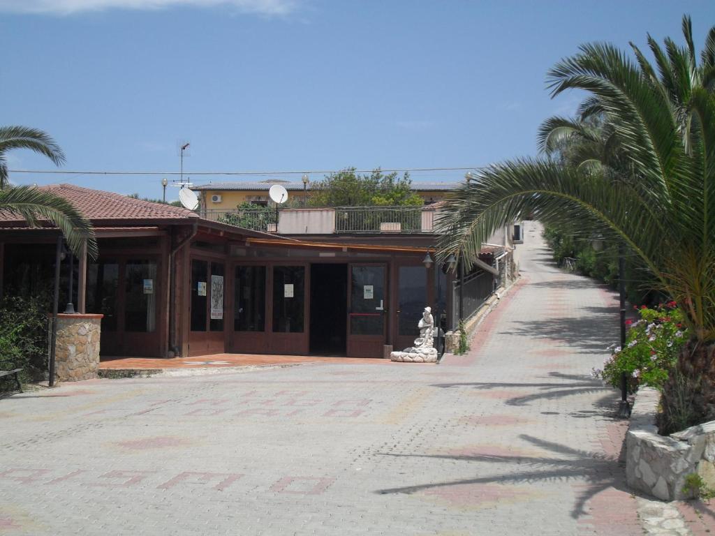 a building with palm trees in front of a street at Agriturismo La Targa in Buonfornello
