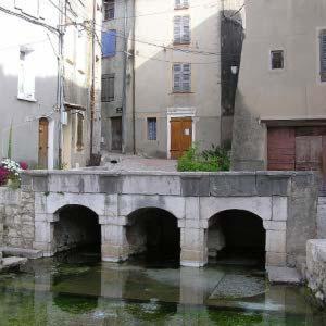 un pont en pierre sur une rivière dans une ville dans l'établissement Maison de village, au calme., à Camps-la-Source
