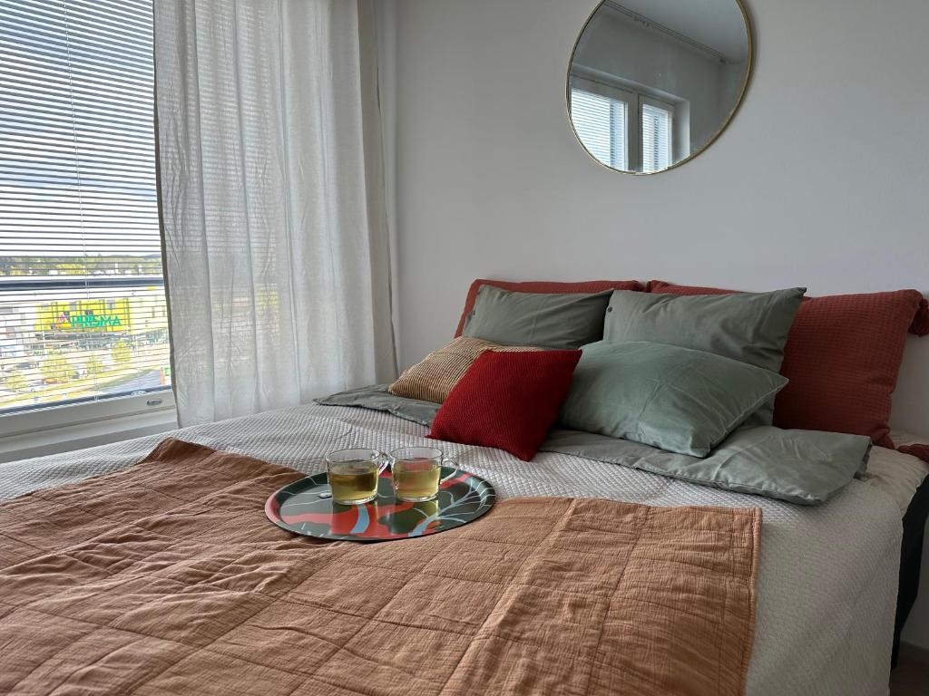 a tray with two drinks on a bed with a mirror at Near center w/ smart-TV, tram stop and gym visit in Tampere