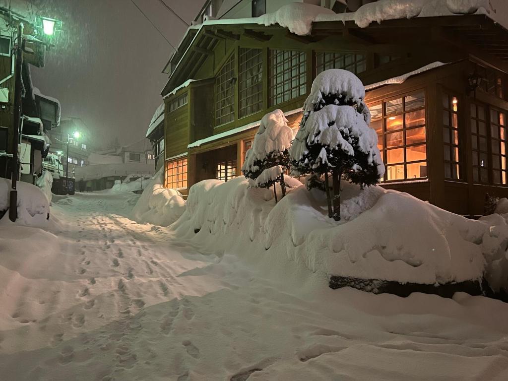 a street covered in snow in front of a house at Kihachikan North Nozawa Onsen in Nozawa Onsen