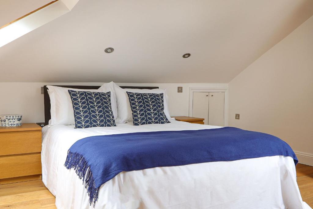 a bedroom with a large bed with blue and white pillows at Bright and Modern 2 bed flat in London
