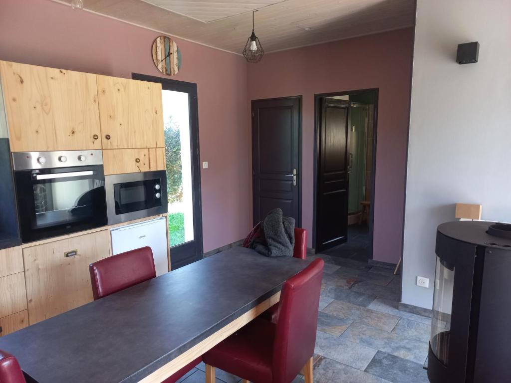eine Küche mit einem großen Holztisch und roten Stühlen in der Unterkunft Home Relax Perche : gîte avec prestations bien-être in Montigny-le-Chartif