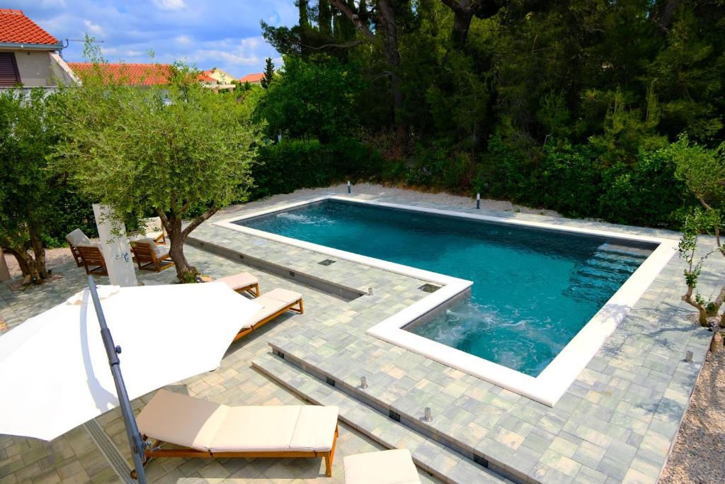 a swimming pool in a yard with two chairs and a table at Villa Gem in Mravince