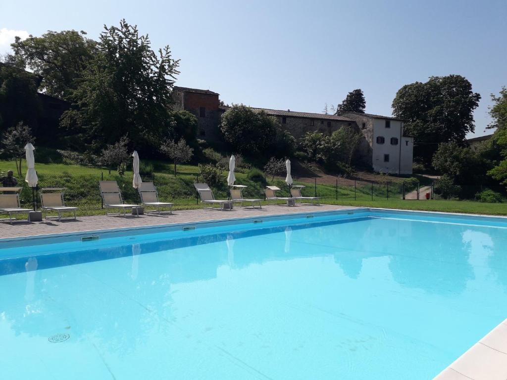 una piscina con sedie e un edificio sullo sfondo di Fattoria di Marena a Bibbiena