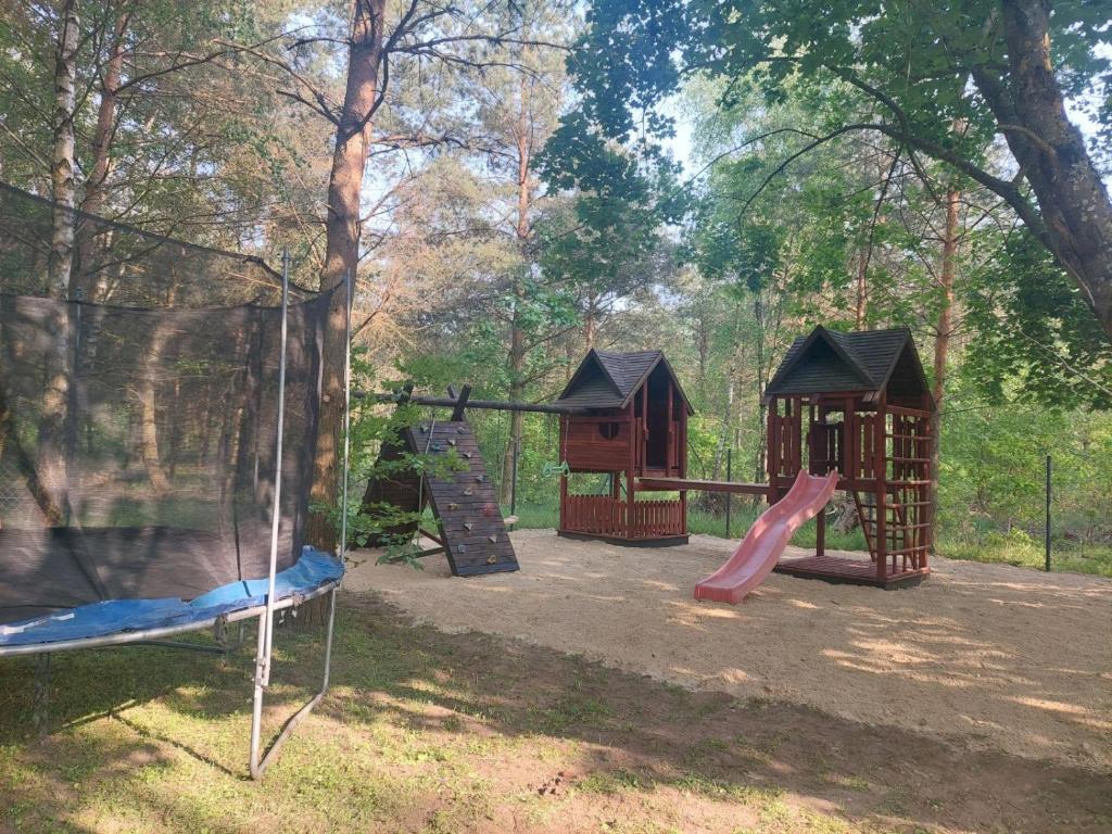 a playground with two play structures and a slide at Dom wypoczynkowy w lesie nieopodal jeziora in Szteklin