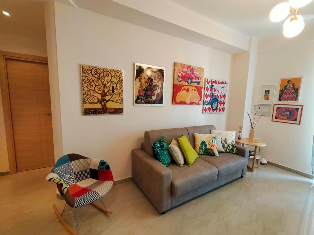 a living room with a couch and paintings on the wall at A casa di Carola. Appartamento in centro dove sentirsi a casa in Molfetta