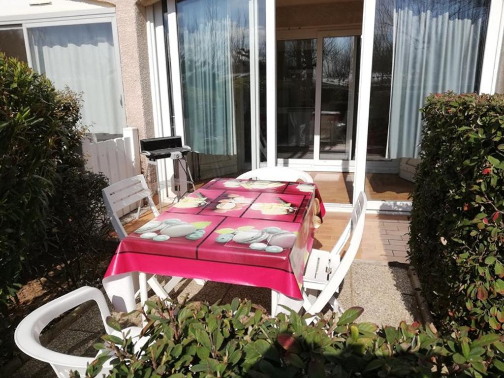 - une table avec une nappe rose et des chaises sur la terrasse dans l'établissement Studio Cabine 4 Pers avec Véranda et Parking Privé – Proche Quai de Plaisance à Marseillan - FR-1-326-489, à Le Castellas