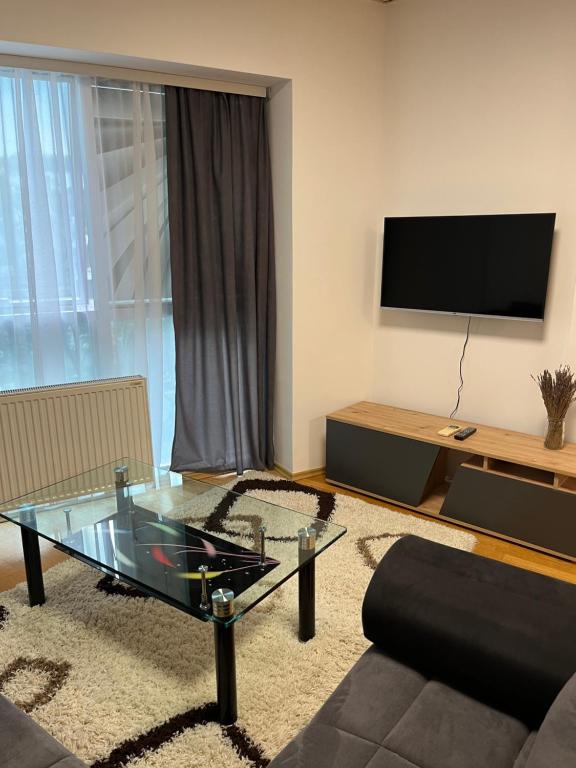 een woonkamer met een glazen salontafel en een flatscreen-tv bij Apartman 208 in Novi Sad