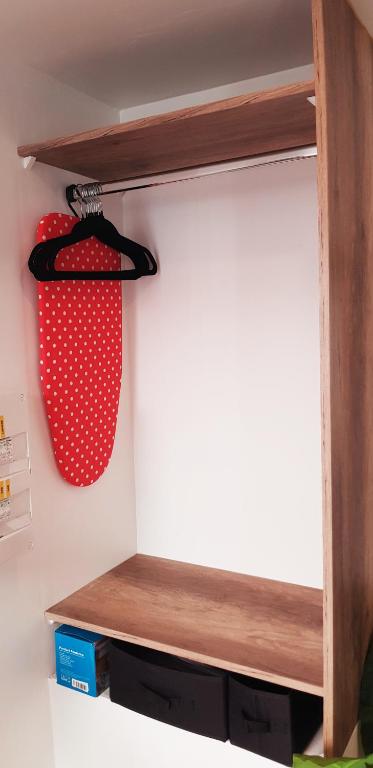 a red basket is hanging on a wooden shelf at Escapade Niortaise - Studios climatisés hyper-centre de Niort in Niort