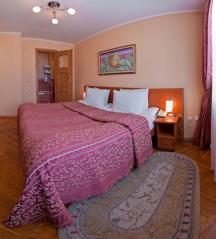 利沃夫赫特曼酒店的卧室里有一张大床,床罩是粉色的
