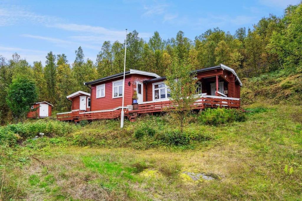 Cozy and spacious cabin في Svensby: منزل خشبي على تلة في ميدان
