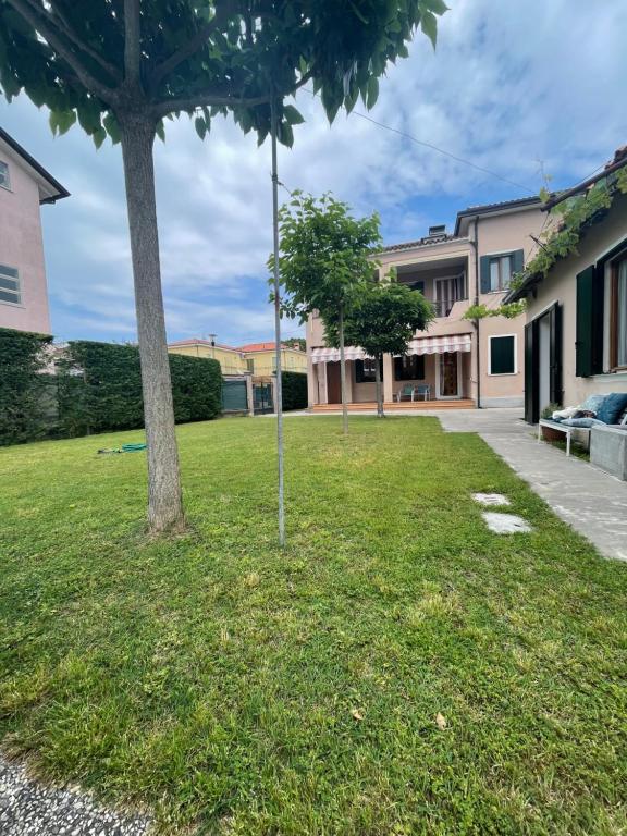 un patio de césped con una palmera frente a un edificio en A Casa dei Nonni, en Cavallino-Treporti