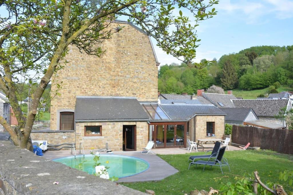 a stone house with a swimming pool in the yard at Granny Cottage. in Marchin