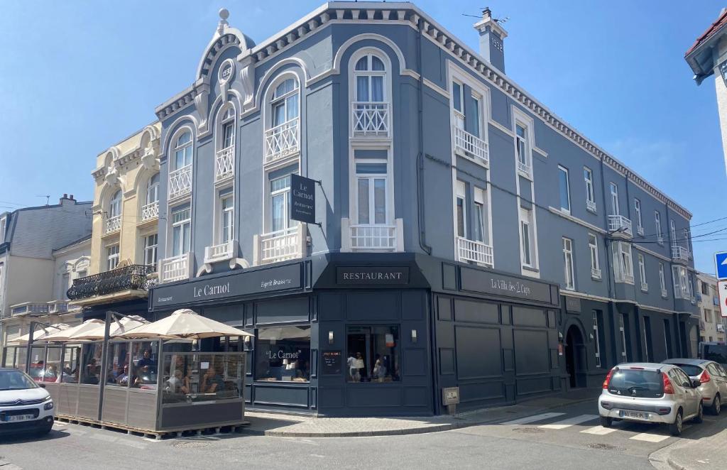 a large blue building on a street with parked cars at Hôtel Villa Des 2 Caps in Wimereux