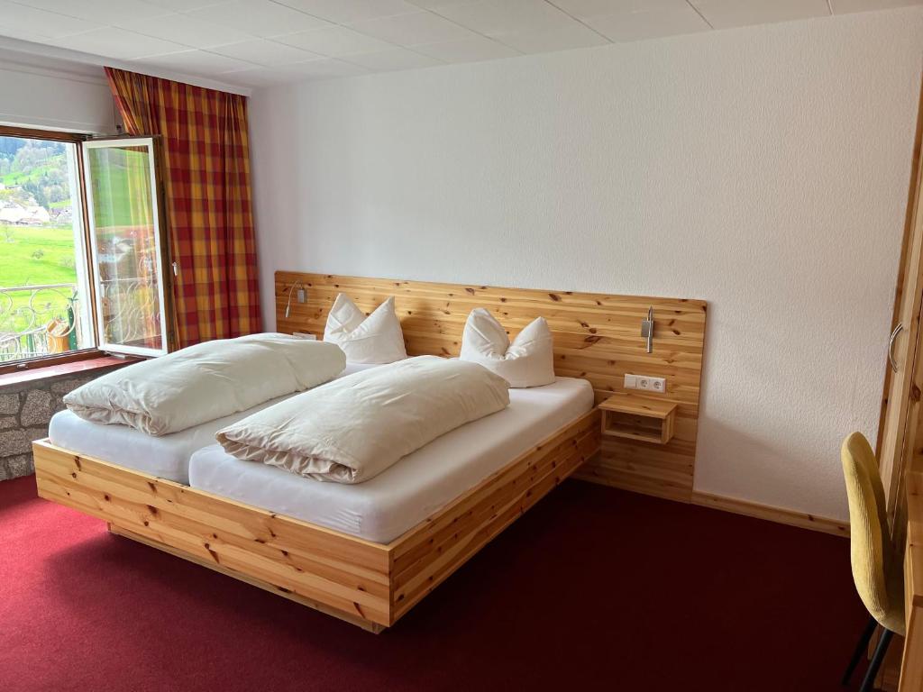 una camera con letto in legno, cuscini e finestra di Gasthaus Pension Eicherg a Glottertal