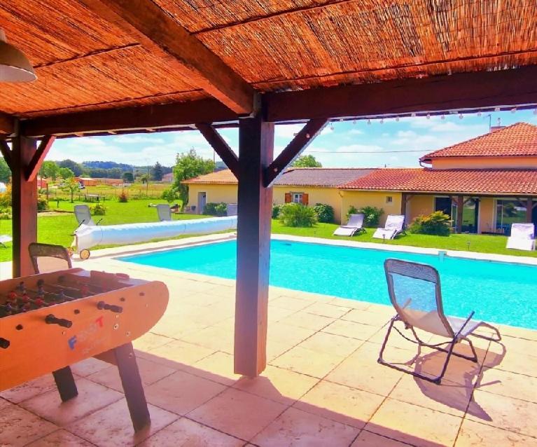 um pátio com uma mesa e cadeiras ao lado de uma piscina em Le Domaine de Laurolie em Gaujacq