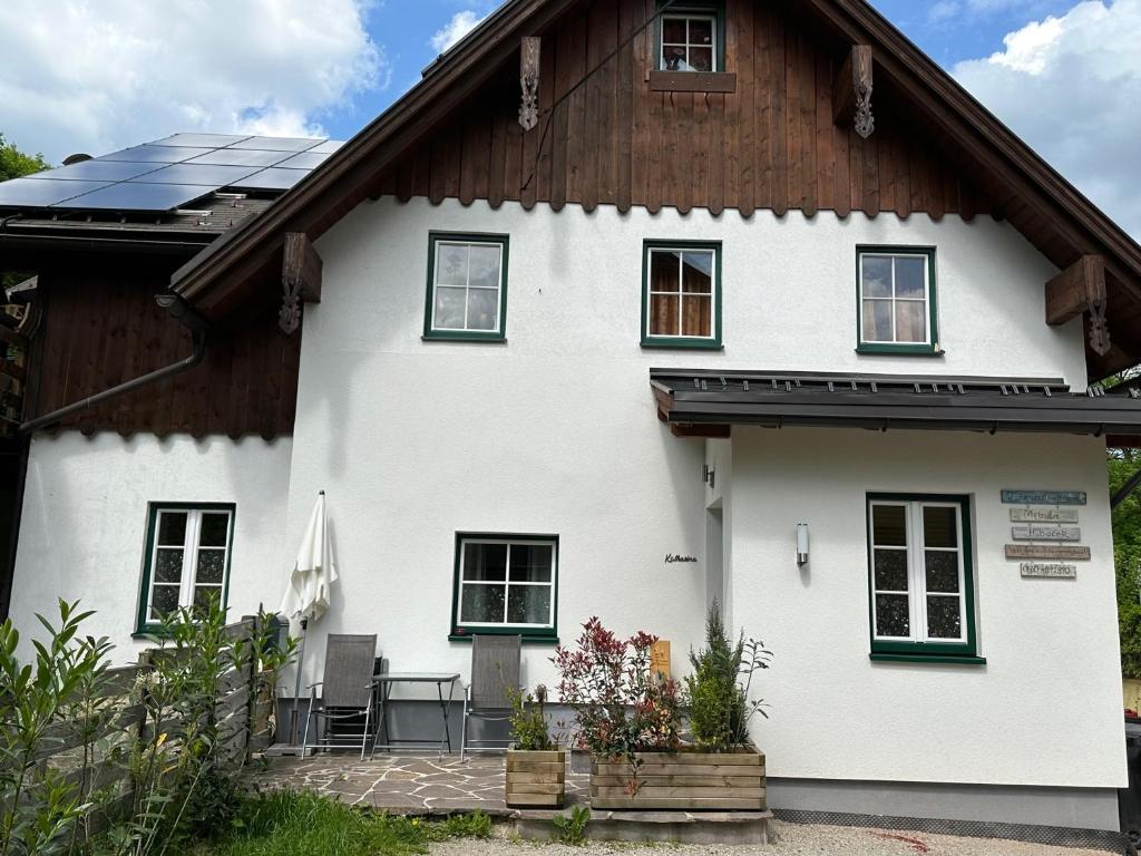 a white house with a wooden roof with a patio at Ferienwohnungen Mikula-Hubacek in Bad Aussee