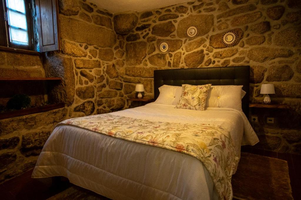 1 dormitorio con 1 cama en una pared de piedra en Casa do Charco Peneda Gerês, en Parada