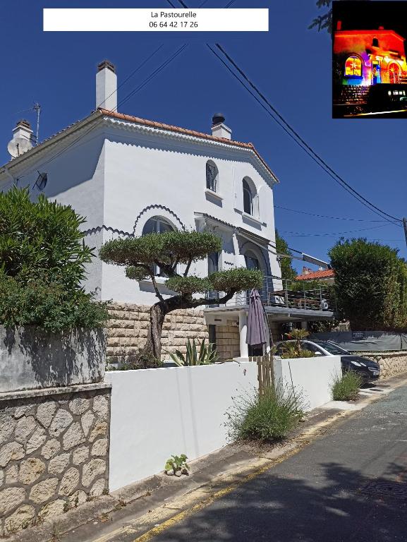 une maison blanche avec un arbre devant dans l'établissement Chambres d'Hôtes LA PASTOURELLE Royan centre, à Royan