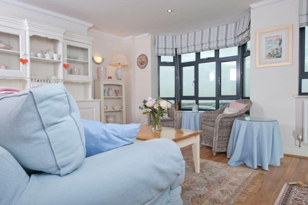 a living room with a blue couch and a table at Little Ships overlooking the Royal Harbour in Kent