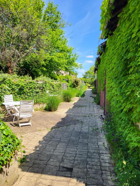 a cobblestone path in a garden with two white benches at Hôtel La Flambée in Bergerac