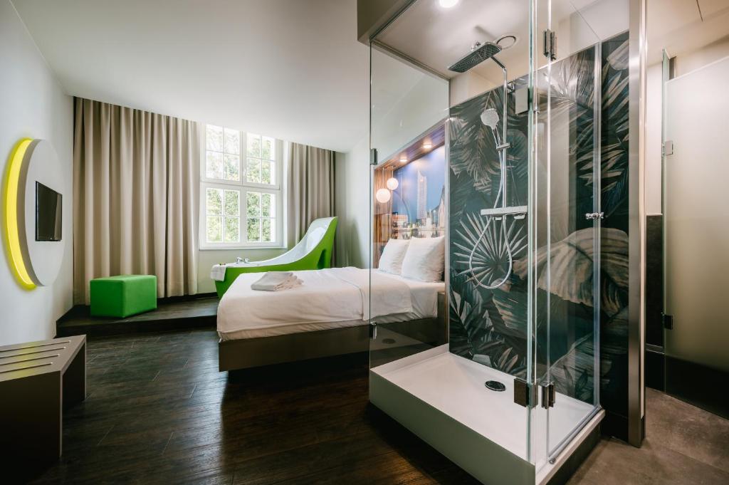 a hotel room with a bed and a glass shower at Travel24 Hotel Leipzig City in Leipzig