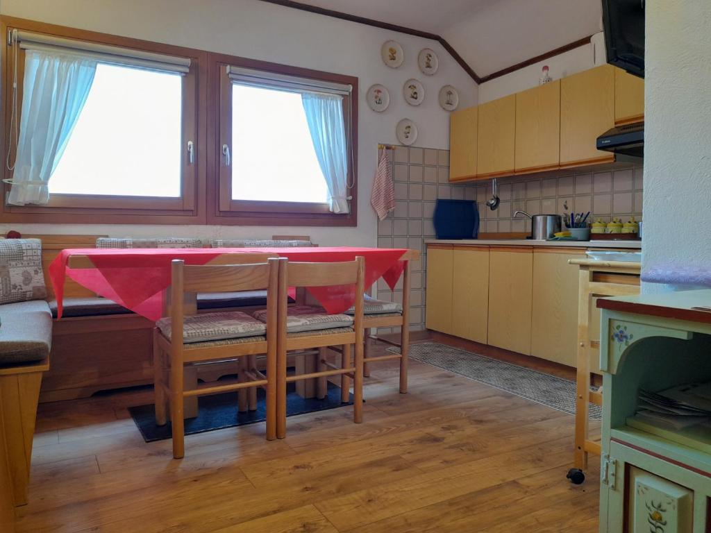 eine Küche mit einem Tisch und einem roten Tischtuch darauf in der Unterkunft Piccolo Igloo in Falcade