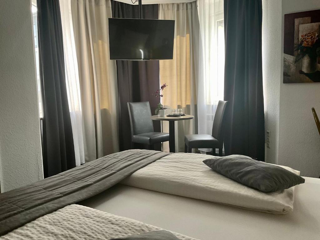 a bedroom with a bed with two chairs and a table at Hotel Royal in Villingen-Schwenningen