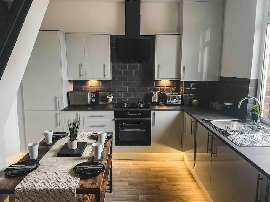 uma cozinha com armários brancos e uma bancada em Comfortable Home In Bolton em Farnworth