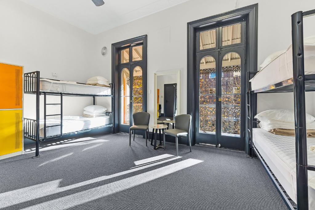 雪梨的住宿－London Plane Backpackers，一间卧室配有双层床和桌椅