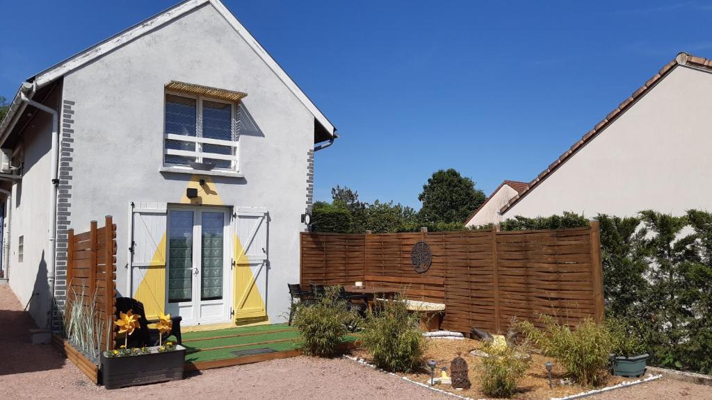 a white house with a wooden fence in front of it at LE FER A CHEVAL in Les Bizots