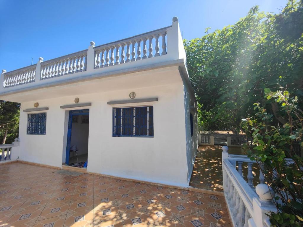 uma casa branca com um alpendre e uma cerca em Maison de vacances avec vue sur mer proche Tanger em Alcácer-Ceguer