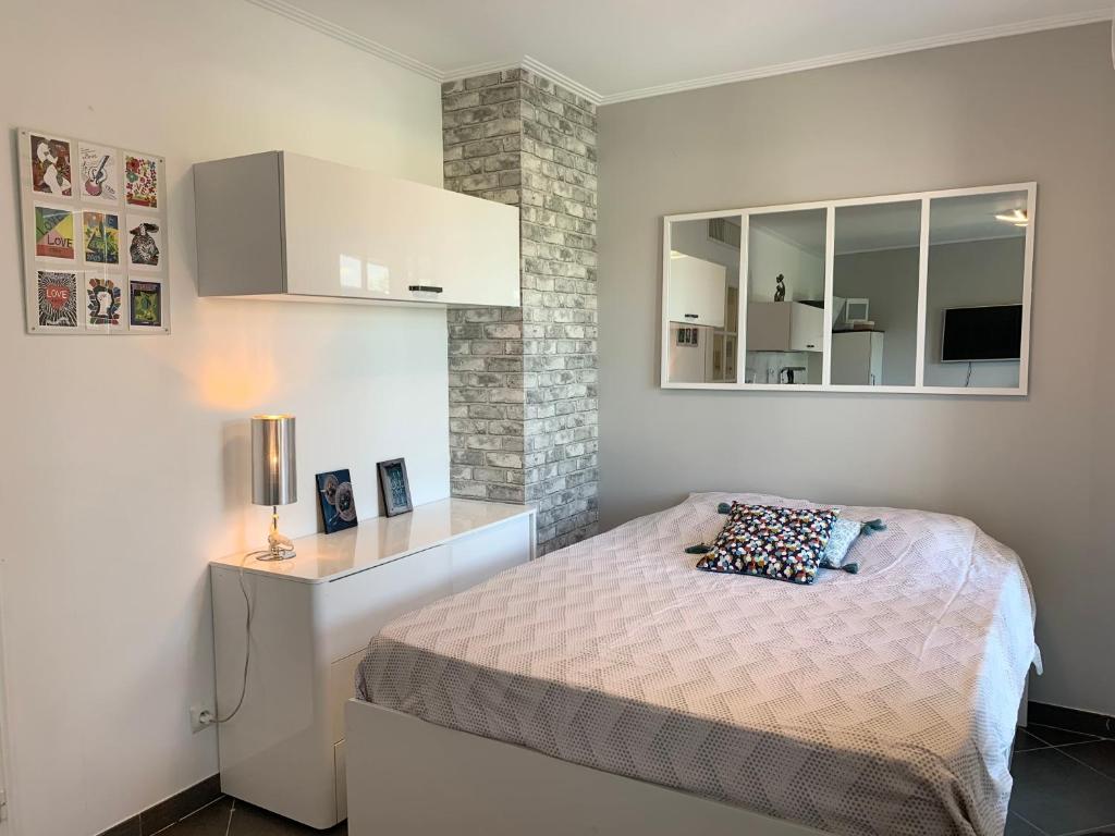 une petite chambre avec un lit et un miroir dans l'établissement Joli studio climatisé avec Jardin dans résidence avec piscine, à Antibes