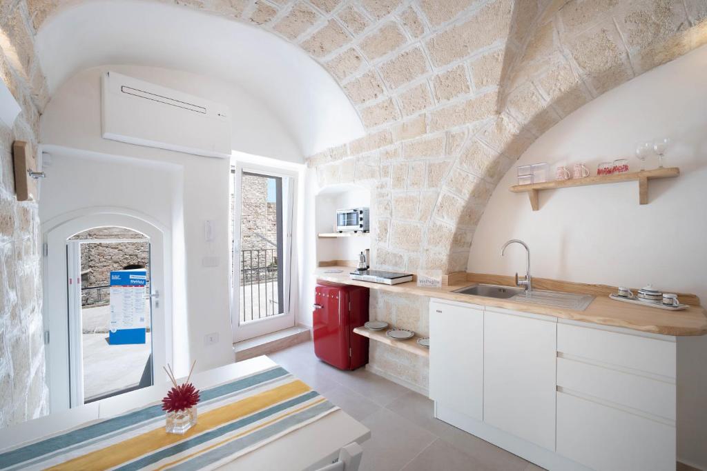 eine Küche mit weißen Schränken und einer Ziegelwand in der Unterkunft WePuglia - Al Castello di AMEC - Apt Emanuela in Monopoli