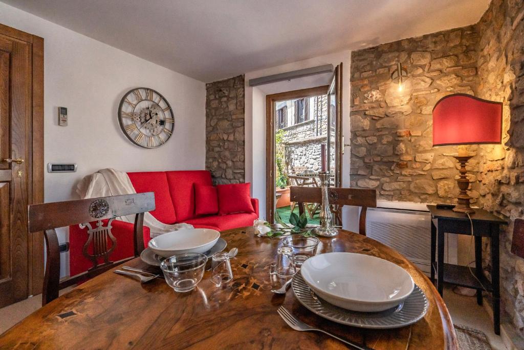 Romantic apartment with terrace في Nievole: غرفة طعام مع طاولة وأريكة حمراء