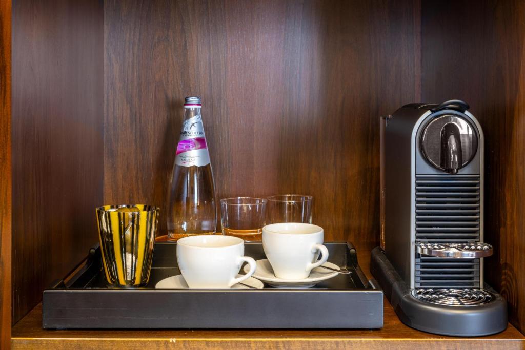 a tray with two cups and a bottle and a coffee maker at Palazzo Bembo - Exclusive Accommodation in Venice