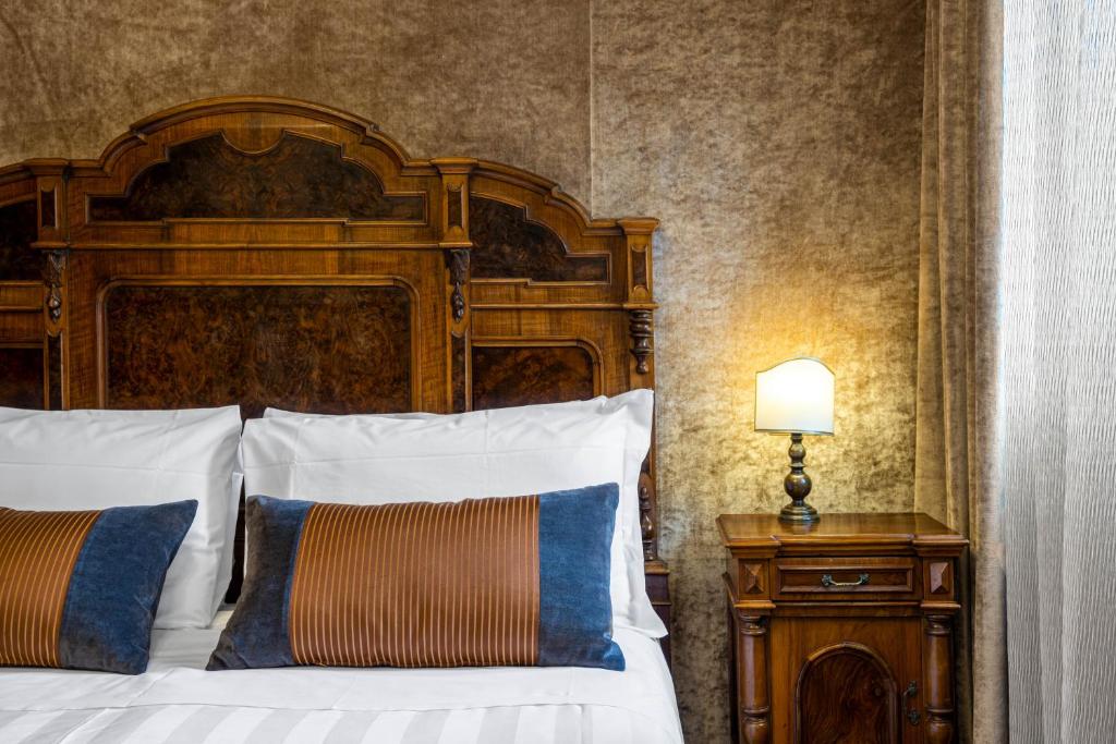 a bedroom with a large bed with a wooden headboard at Palazzo Bembo - Exclusive Accommodation in Venice