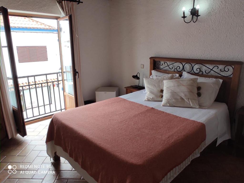 a bedroom with a large bed and a balcony at Zé Inácio - Alojamento e Restaurante in Porto Covo