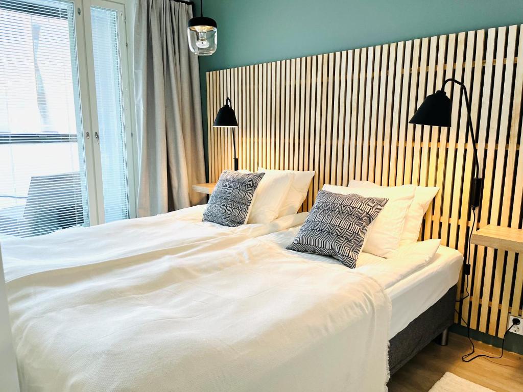 um quarto com uma grande cama branca e 2 almofadas em Uusi upea kaksio Tampereen ytimessä, pysäköinti, iso lasitettu parveke em Tampere