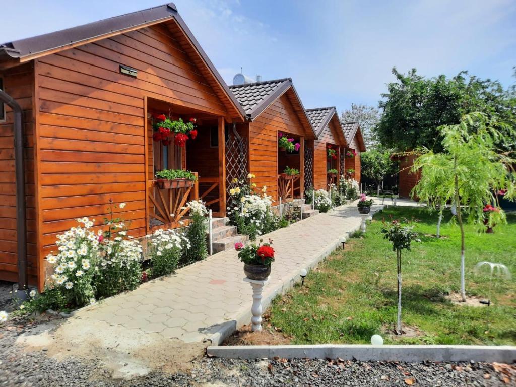 a row of wooden houses with flowers in the yard at Cabanele Deltei in Dunavăţu de Jos