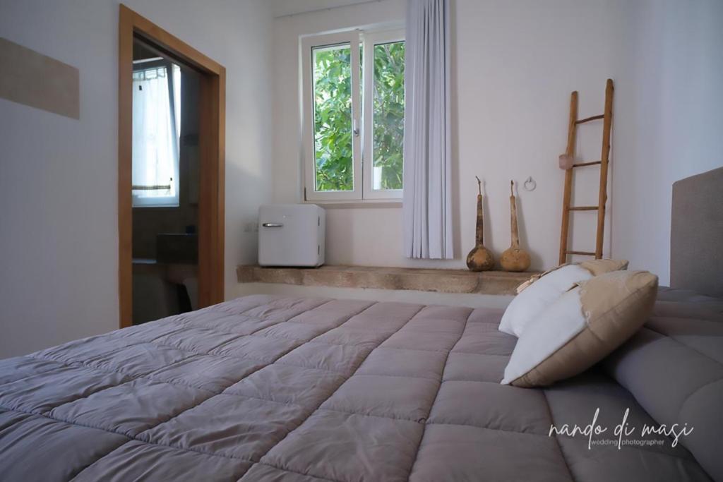 a bedroom with a large bed and two windows at Masseria Giangrande - Rooms and Apartment in Polignano a Mare