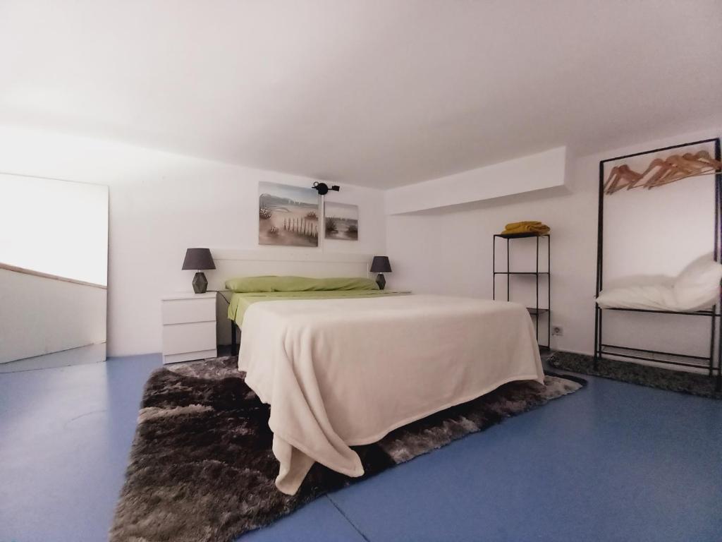 Habitación blanca con cama y espejo en Vivienda San Justo, en Las Palmas de Gran Canaria