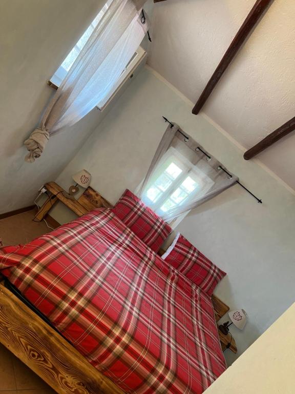 a bedroom with a red plaid bed with a window at Camera Delux matrimoniale in Serina