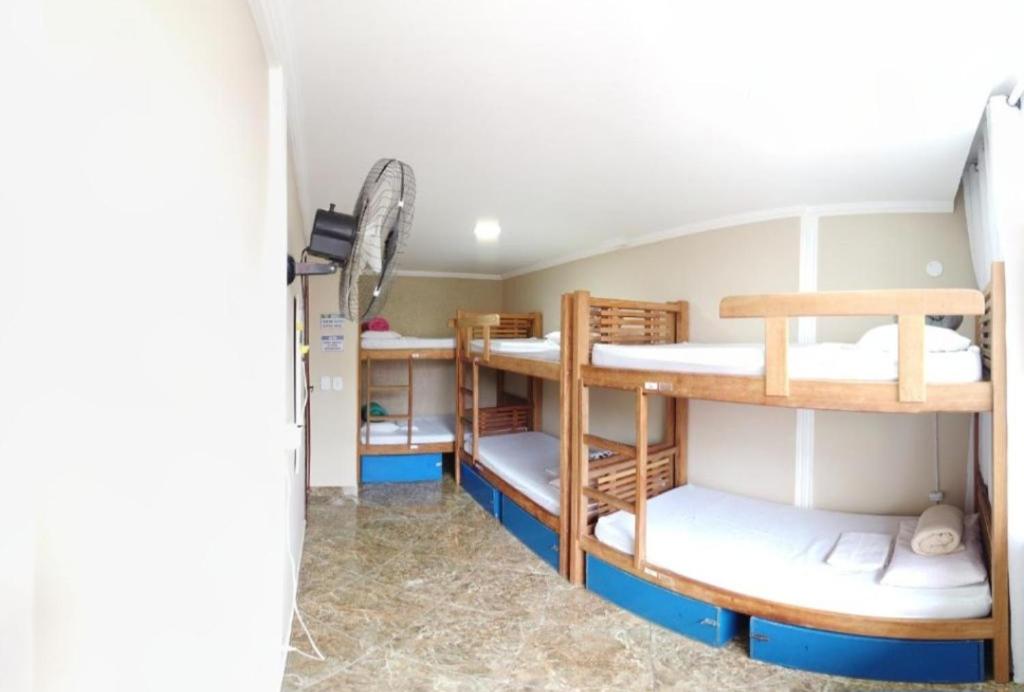 a room with three bunk beds in a house at Nossa Casa Arraial HOSTEL e SUÍTE in Arraial do Cabo